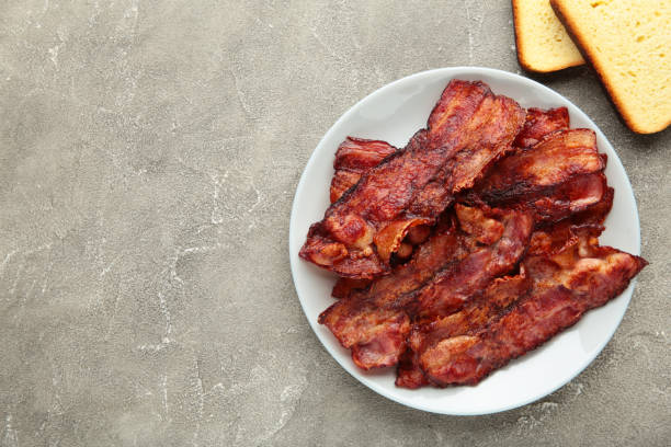 istock Bacon fried slices in plate on grey background. Top view 1308412228