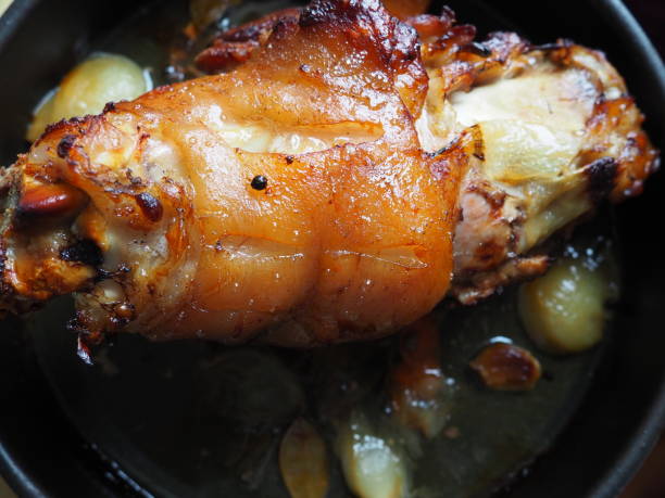 Pork knuckle baked on a baking sheet in the oven with onions, carrots and spices. Delicious restaurant or homemade dish for a festive lunch or dinner. Fatty high-calorie male food. Oven-cooked meat. nudillo de cerdo horneado en una bandeja para hornear en el horno con cebollas, zanahorias y especias. delicioso restaurante o plato casero para un almuerzo o cena festivo. alimentos masculinos grasos con alto contenido calórico. carne cocida al horno