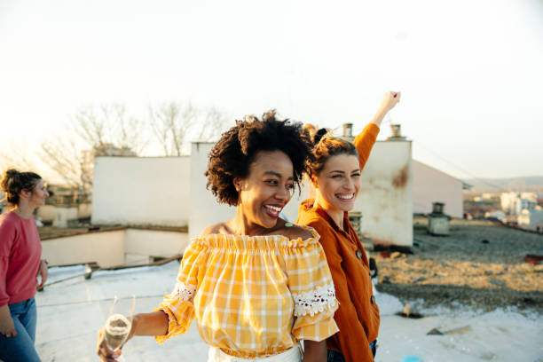 Girlfriends having a great time on a rooftop Photo of smiling young women having a great time during the rooftop party; celebrating their friendship, femininity, and youth. ladies night stock pictures, royalty-free photos & images