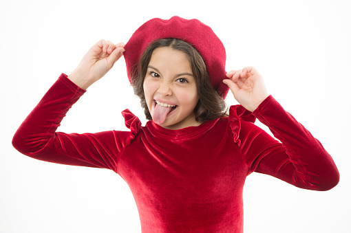happy girl showing tongue. kid from paris. French style child. Parisian girl in beret. Cute girl with dark hair. Stylish brunette. fashion portrait of funny girl wearing trendy hat. just have fun.