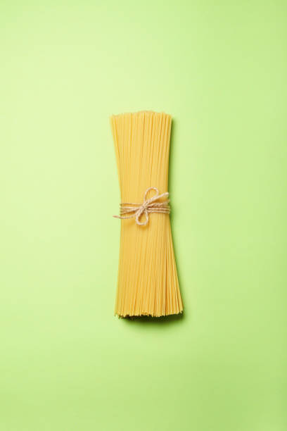 istock Yellow long spaghetti on a green paper background. 1308414985