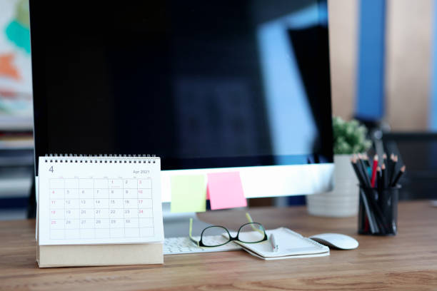 istock Loose leaf paper calendar standing near computer on desktop closeup 1308416150
