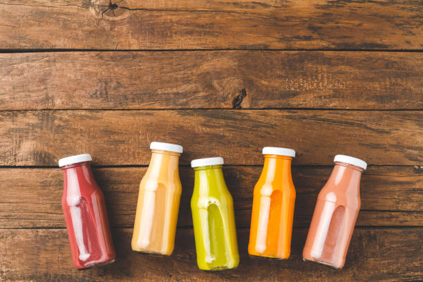 istock Colourful smoothies on old wooden table with copyspace. Fresh juices in bottles 1308416461