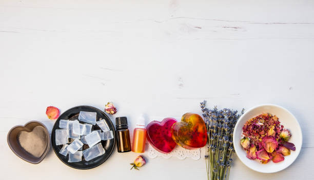Making handmade soap with crystal clear melt and pour soap mixture. Ready to use pink and yellow tied soaps with rose petals and lavender blossoms with ingredients. Lot of empty room for text.