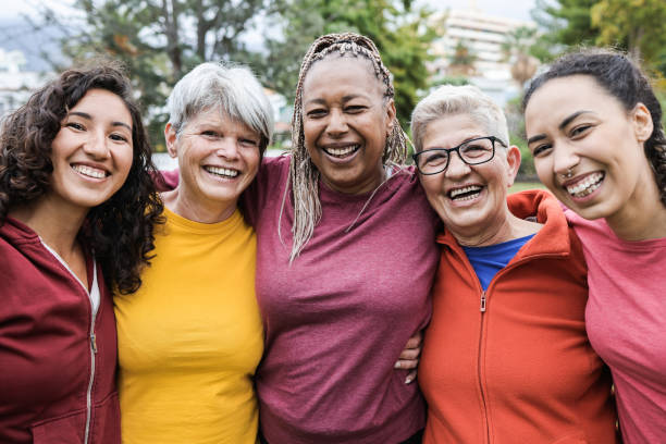 mujeres multigeneracionales felices divirtiéndose juntas - amigos multirraciales sonriendo en la cámara después del entrenamiento deportivo al aire libre - enfoque principal en la cara femenina africana - yoga fotos fotografías e imágenes de stock