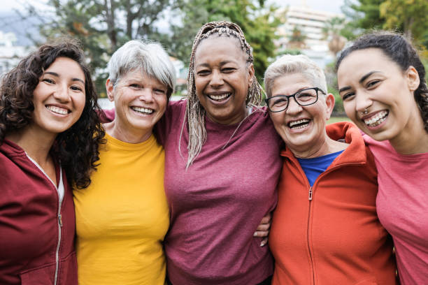 Happy multi generational women having fun together - Multiracial friends smiling on camera after sport workout outdoor - Main focus on african female face Happy multi generational women having fun together - Multiracial friends smiling on camera after sport workout outdoor - Main focus on african female face group of women all ages stock pictures, royalty-free photos & images
