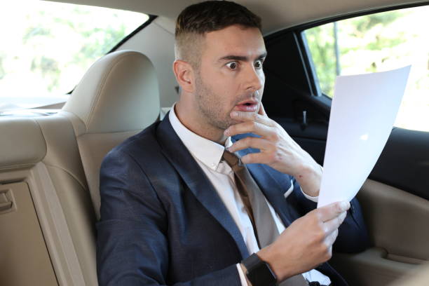 istock Worried businessman reading document in taxi 1308420088