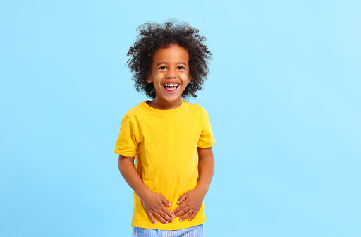 Niño afroamericano positivo riendo en estudio azul photo