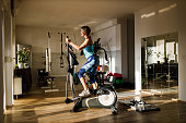 Happy athletic woman cycling on exercise bike