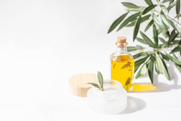 istock A glass jar with olive oil and olive tree twig are on white background. 1308422052