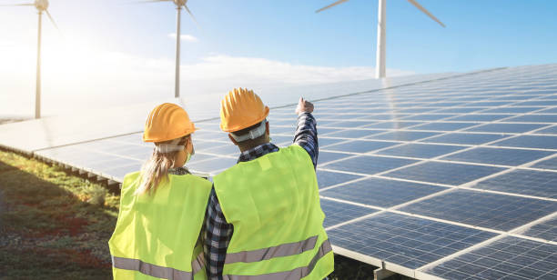 personnes travaillant pour le parc d’énergie alternative - processus de générateurs d’énergie d’éolienne et panneaux solaires - focus sur des casques - solar panel engineer solar power station women photos et images de collection