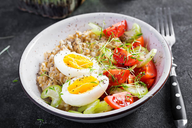 istock Breakfast oatmeal porridge with boiled egg, cherry tomatoes, celery and microgreens. Healthy balanced food. 1308425052