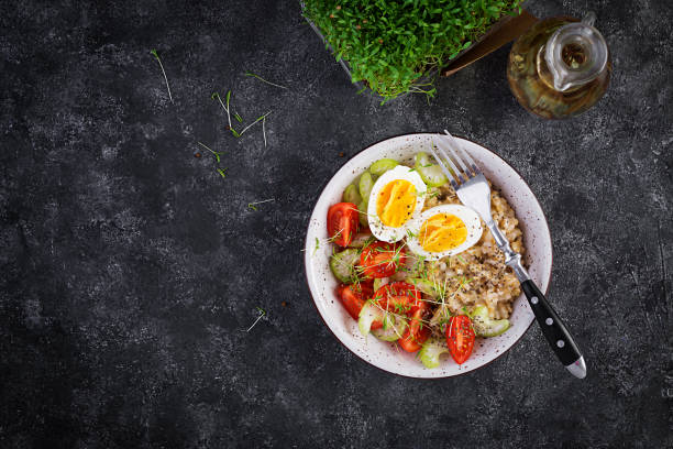 istock Breakfast oatmeal porridge with boiled egg, cherry tomatoes, celery and microgreens. Healthy balanced food. Top view, above, copy space 1308425053