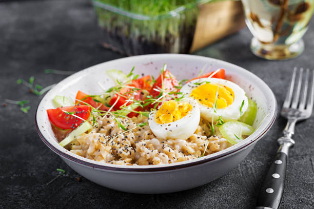 istock Breakfast oatmeal porridge with boiled egg, cherry tomatoes, celery and microgreens. Healthy balanced food. 1308425057