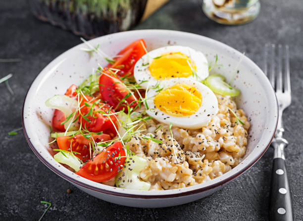 istock Breakfast oatmeal porridge with boiled egg, cherry tomatoes, celery and microgreens. Healthy balanced food. 1308425061