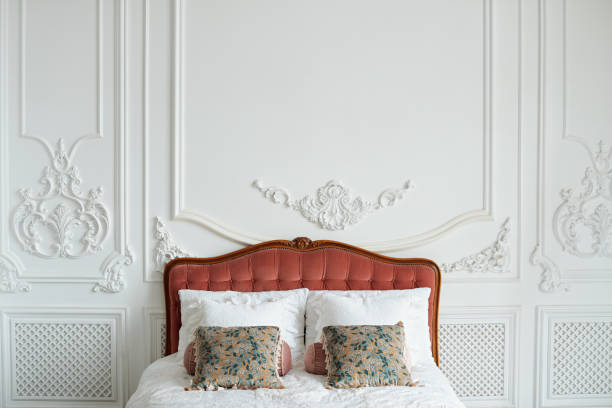роскошный богатый интерьер спальни в светлых цветах. большая удобная двуспальная королевская кровать с различными подушками в элегантном  - antique bed стоковые фото и изображения