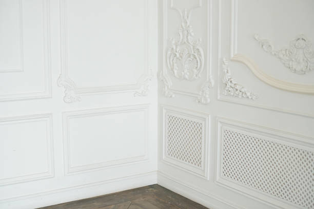 istock White walls with an elegant panel made using stucco moldings and wooden flooring in the corner of empty room, interior design elements. Home interior, empty room. Copy space. 1308425073