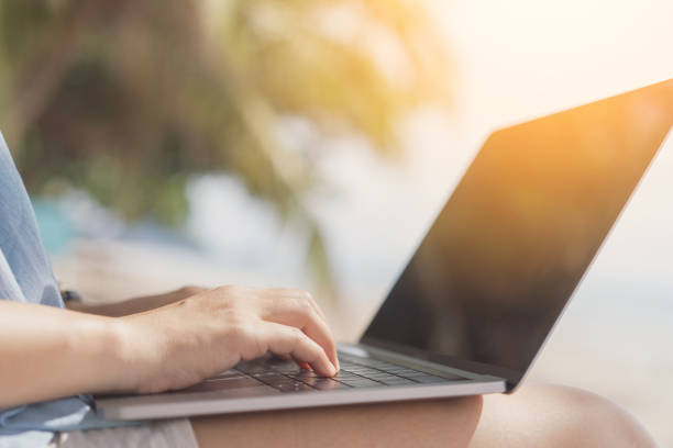 istock Woman using laptop on tropical beach background. 1308425117