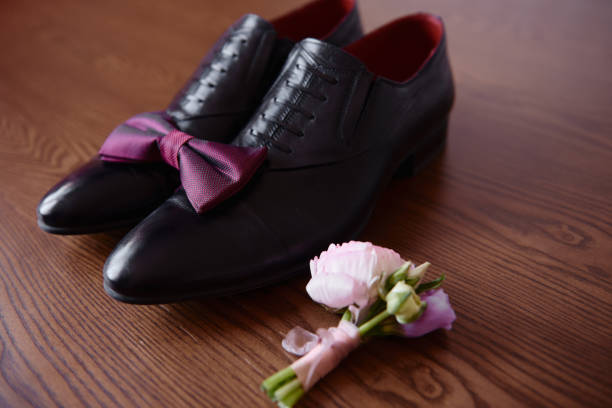 nahaufnahme von schwarzen männlichen schuhen, fliege und boutonniere auf holzboden hintergrund, kopierraum. moderne mann zubehör. hochzeitsdetails - shoe groom wood luxury stock-fotos und bilder