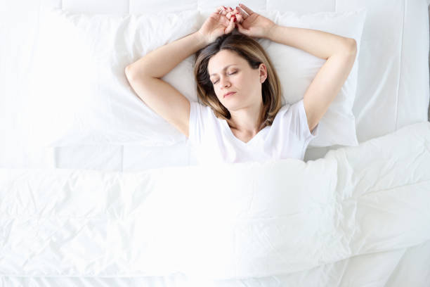 istock Young woman sleeping in white bed top view 1308426675