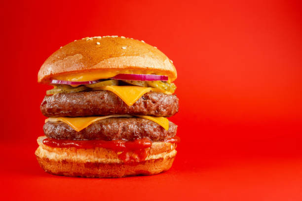 istock Delicious burger with double beef and cheddar cheese on a red background. Tasty fresh unhealthy burgers with cheese and two patties. Fast food, unhealthy food concept. 1308428273