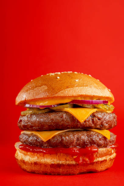 istock Delicious burger with double beef and cheddar cheese on a red background. Tasty fresh unhealthy burgers with cheese and two patties. Fast food, unhealthy food concept. 1308428283