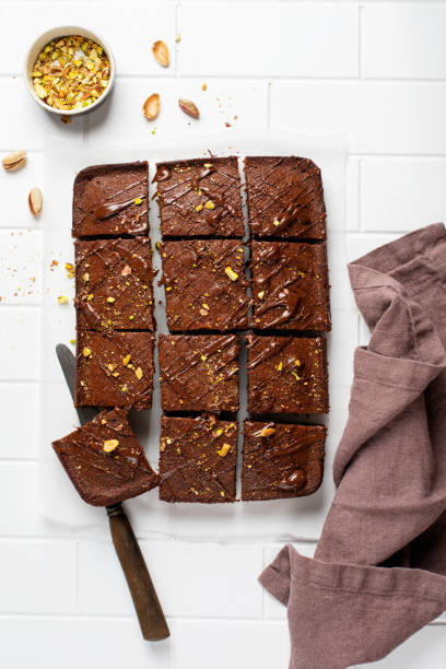 istock Chocolate squares with pistachio nuts and strawberries on white paper on a light background, top view, horizontal composition. Flat food 1308429489
