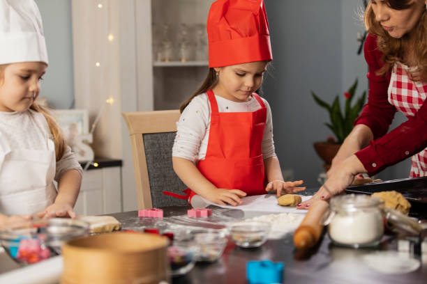 istock Woman assisting her two little daughters in making dough for gingerbread cookies 1308430502
