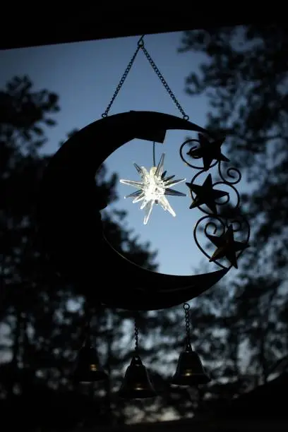 This is a silhouette of a metal moon with three bell chimes and a glow in the dark star.