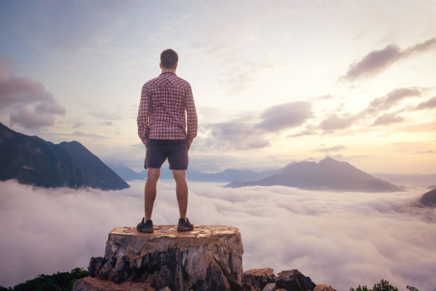 istock Man standing on a mountain top above the clouds 1308431297