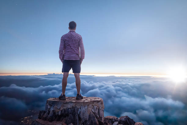 istock Man on a mountain top enjoying the view over the clouds 1308431299