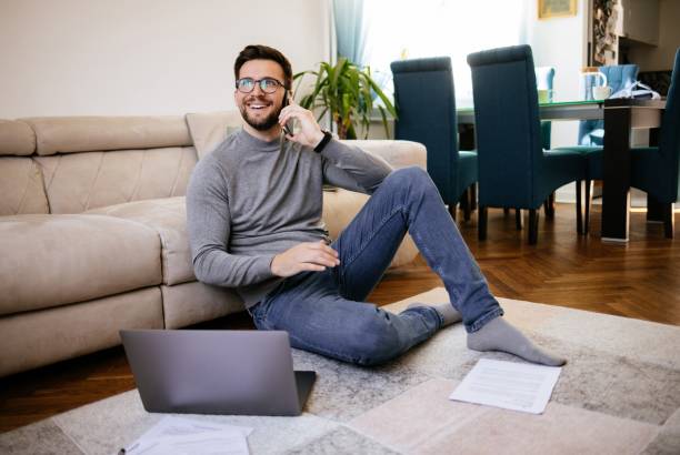 istock Mid adult man using his smart phone and laptop while working at home 1308432667