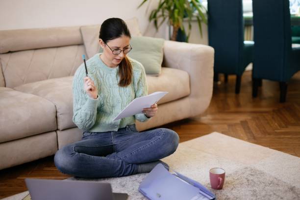 istock Mid adult woman analyzing documents while working on laptop from home 1308432787