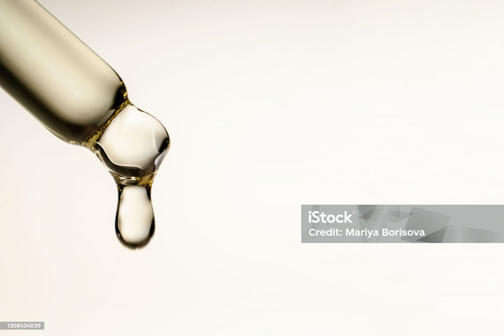 A drop of cosmetic oil falls from the pipette A drop of cosmetic preparation falls from a pipette filled with bubbles. Perfect for showcasing your product. Pipette Stock Photo