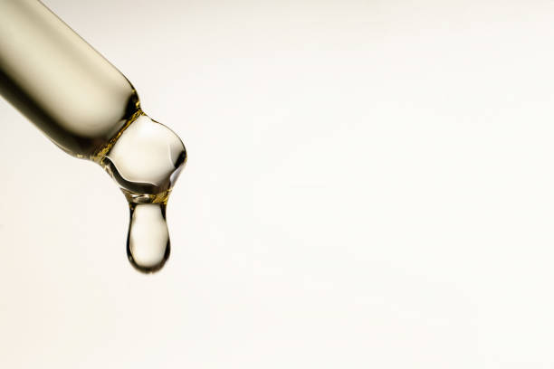 a drop of cosmetic oil falls from the pipette - pipeta imagens e fotografias de stock