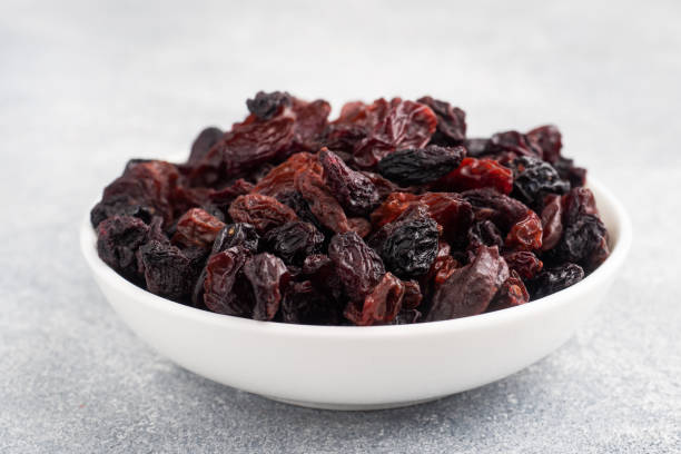 istock Dried raisins from dark grapes in a plate on a gray concrete background, copy space. top view 1308436080