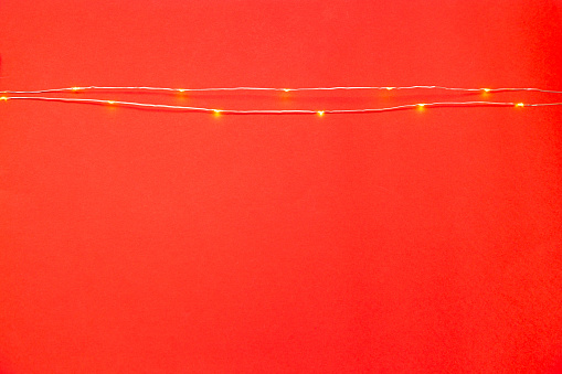 abstract red background with lit LED garland lights. top view
