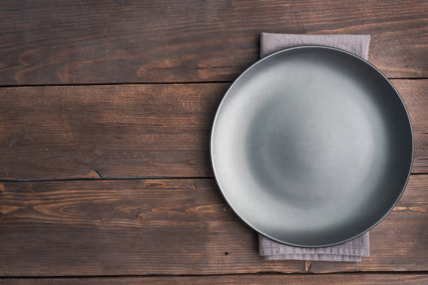istock Empty black plate on wooden rustic background. Top view with copy space. 1308437707