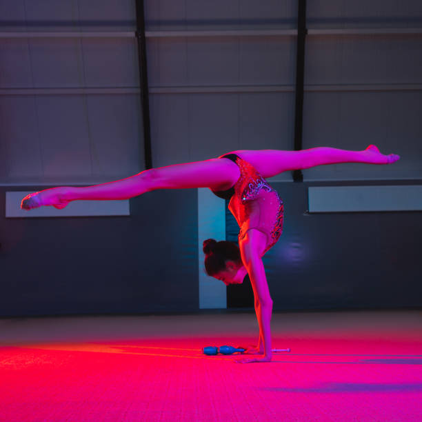 istock Young female rhythmic gymnast isolated on multicolored background in neon light 1308441534