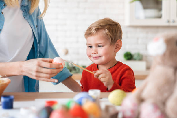 istock Cute small boy helping his mom with eggs decoration for Easter 1308442026
