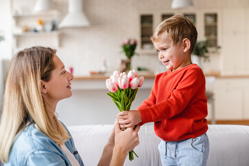 Little cute boy giving his mother tulips as a gift for Easter