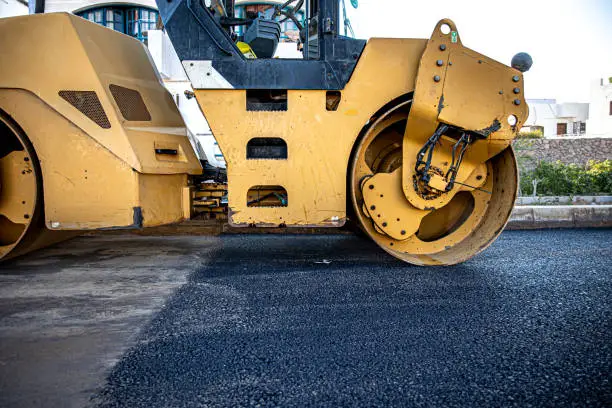 Road roller makes the paving. Road roller compacting asphalt. Roller Compactor on Fresh Asphalt.