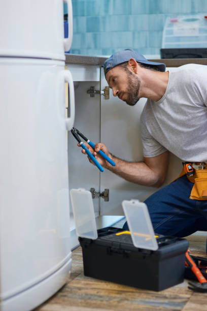 istock Professional repairman looking focused, using pipe wrench while examining and fixing sink pipe in the kitchen 1308444378