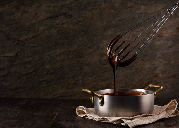 istock Liquid chocolate cream pouring from a whisk into a ladle. 1308444667