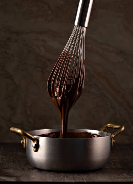istock Liquid chocolate cream pouring from a whisk into a ladle. 1308444671
