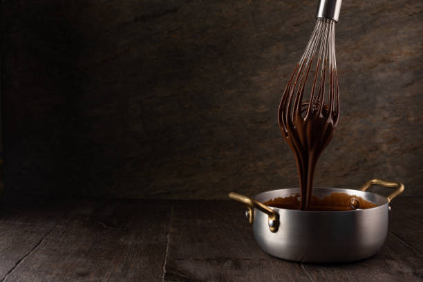 istock Liquid chocolate cream pouring from a whisk into a ladle. 1308444672