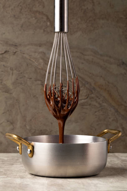 istock Liquid chocolate cream pouring from a whisk into a ladle. 1308444673