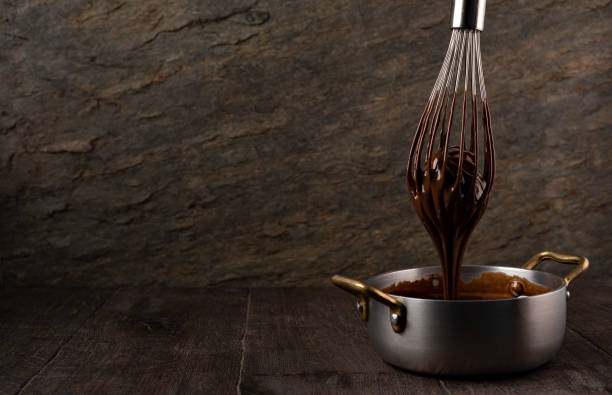 istock Liquid chocolate cream pouring from a whisk into a ladle. 1308444677