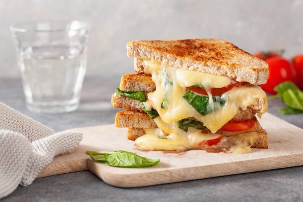 spinaci al formaggio alla griglia e sandwich di pomodoro su sfondo concreto - cheese sandwich foto e immagini stock