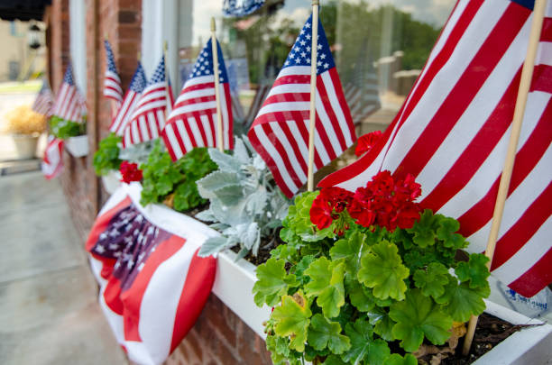 Patriotic Homes and Neighborhoods and the Celebration of Independence Day The American Dream is pictured in this iconic image of American Flags and bunting decorations placed in a shop window. american flag bunting stock pictures, royalty-free photos & images
